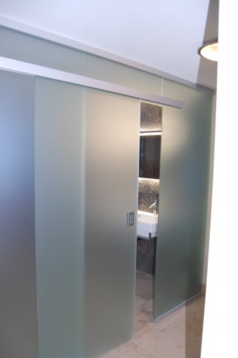 Glastrennwand mit integrierter Schiebetüre als Badzimmerabtrennung